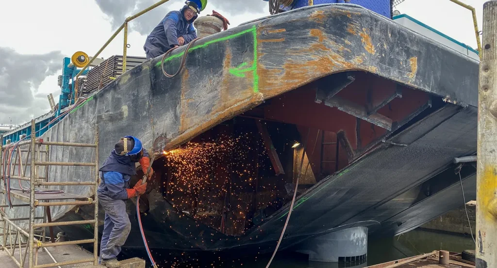 Reparatie van kopschade aan schip door Nieuwenhuijsen. Scheepsbouw